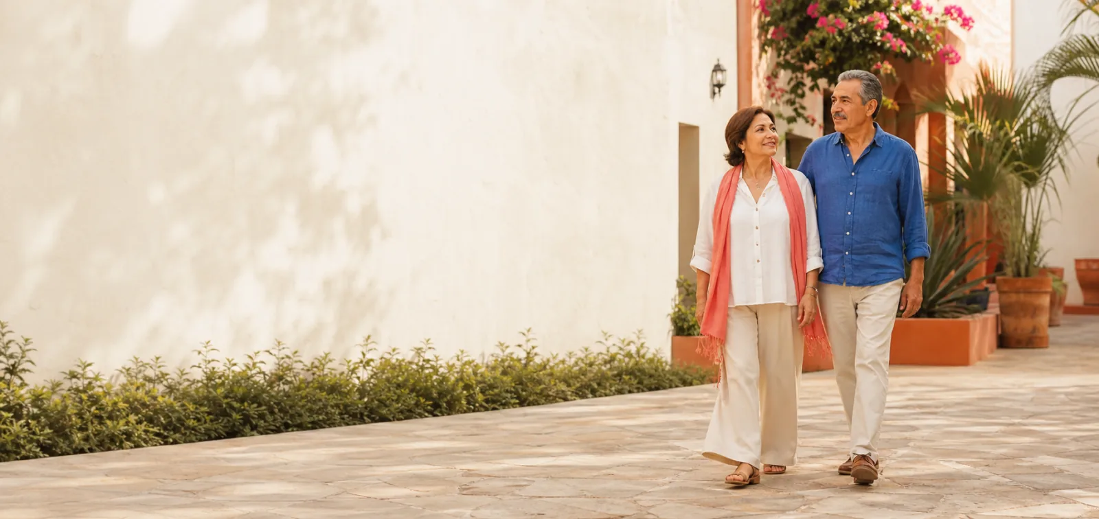 Pareja mexicana camina con tranquilidad por un patio soleado